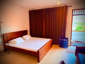 Une chambre d’hôtel avec un lit en bois, un étagère en métal et une vue sur la verdure.