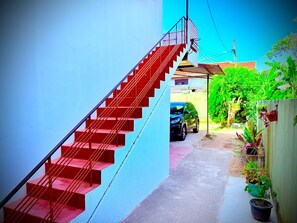 Un escalier menant à une zone abritée où une voiture est garée à l’extérieur.