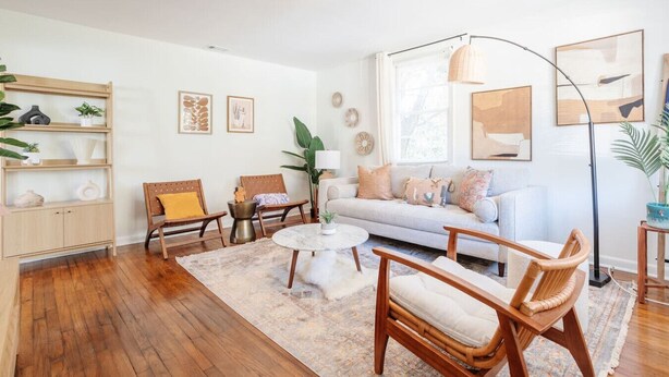 Una sala de estar con sofá, sillones, una mesa de centro, una lámpara de pie y una estantería.