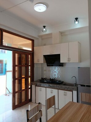 A modern kitchen with white cabinets, a gas stove, a microwave, and a refrigerator. - bluedream (puerto princesa)