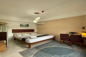 A hotel room with a bed, desk, chairs, and a small rug. - bluedream (puerto princesa)