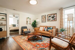 Ein Wohnzimmer mit einer Couch, Sesseln, einem Couchtisch und einem gemusterten Teppich.
