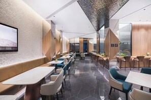 En moderne restaurant med en lang disk, siddepladser med borde og en højloftet, detaljeret loftsdesign.