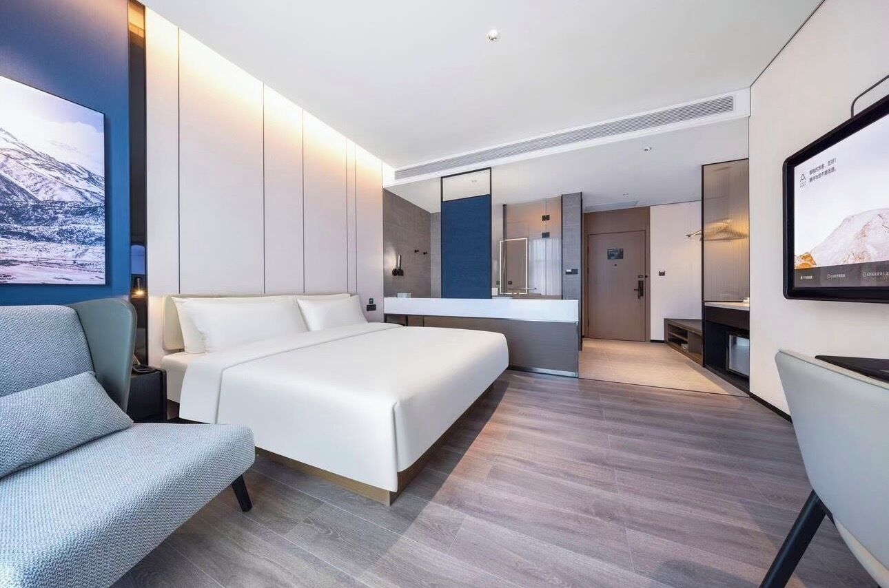 Et moderne hotelværelse med en stor seng, et siddeområde, badeværelse og et fjernsyn.