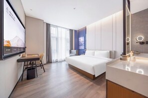 Et moderne hotelværelse med seng, skrivebord, stol, fjernsyn og badeværelse med spejl og lys.