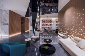 En moderne lobby med reception, siddeområde og en reol.