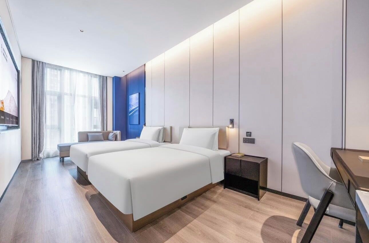 Et moderne hotelværelse med to senge, et skrivebord og en stol.