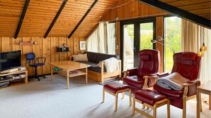 A cozy cabin interior with a wooden ceiling, a sofa, a TV, and leather chairs. - 2 bedroom pet friendly home in Bogø By (Bogø By)