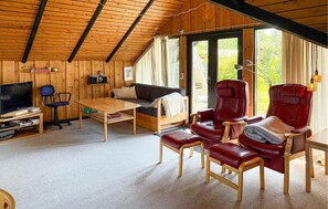 Ein gemütliches Cabin-Interieur mit Holzbalkendecke, einer Couch, einem Fernseher und Ledersesseln.