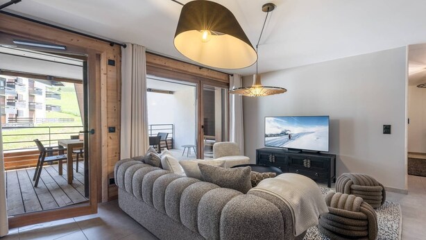 Ein modernes Wohnzimmer mit einem großzügigen Ecksofa, einem Flachbildfernseher und einem Essbereich mit Tisch und Stühlen.