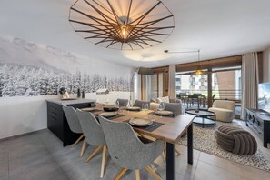 A modern dining area with a central table, chairs, and a unique ceiling light fixture. - Art Mony 209 (CHATEL)