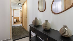 Ein Flur mit einer schwarzen Konsole, zwei Vasen und zwei Spiegeln an der Wand.