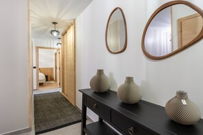 A hallway with a black console table, two vases, and two mirrors on the wall. - Art Mony 209 (CHATEL)