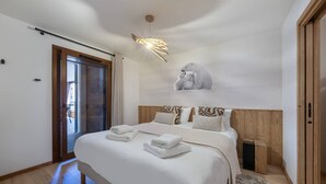 Ein Schlafzimmer mit einem großen Bett, einem hölzernen Kopfteil, einer Eisbärenskulptur und einer modernen Deckenleuchte.