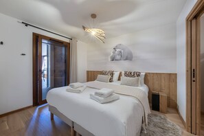 A bedroom with a large bed, a wooden headboard, a polar bear sculpture, and a modern ceiling light. - Art Mony 209 (CHATEL)