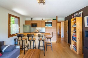 Eine moderne Küche mit Holzausstattung, einer zentralen Kochinsel mit Hockern und einem eingebauten Backofen.