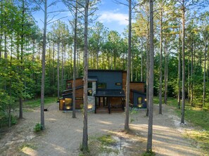 Een moderne cabin omgeven door hoge bomen in een bos.