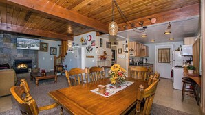 Una sala de estar acogedora con chimenea, una mesa de comedor de madera y sillas.