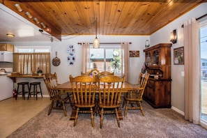 Un comedor con una mesa y sillas de madera, una araña y un mueble de madera con una bandera.