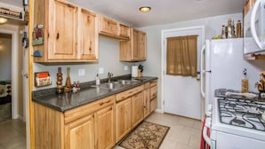 Una cocina con armarios de madera, encimera de granito, estufa y refrigerador.