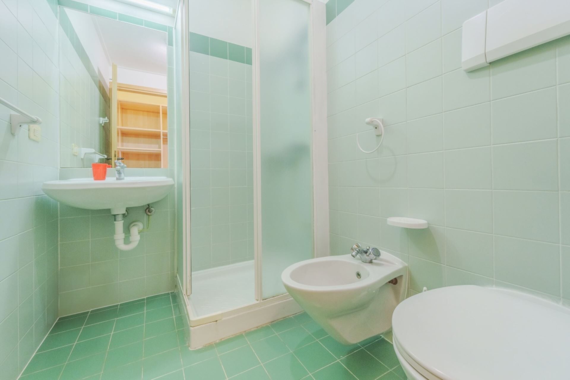 Ein Badezimmer mit Dusche, Waschbecken, Bidet und Toilette.