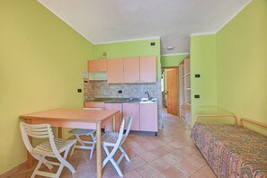Une cuisine compacte avec un coin repas, une petite table et deux chaises.