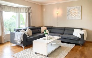 Ein Wohnzimmer mit grauem Sofa, weißem Couchtisch und einem gemusterten Teppich.