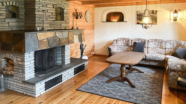 A cozy living room with a stone fireplace, a sofa, and a patterned rug. - 3 bedroom cozy home in ålesund (Ålesund)
