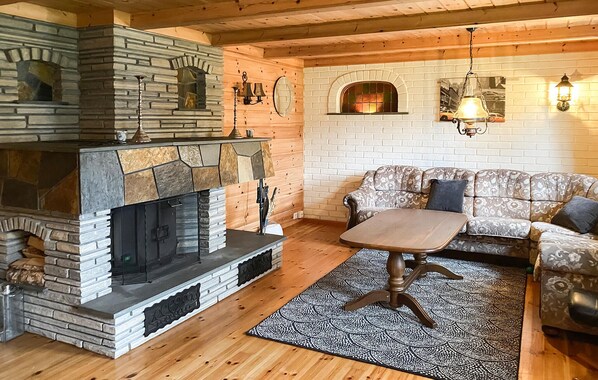 Ein gemütliches Wohnzimmer mit Kamin aus Stein, einer Couch und einem gemusterten Teppich.