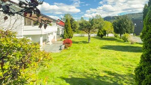 A residential property with a well-maintained lawn, a white house with a red roof, and a large tree in the yard. - 3 bedroom cozy home in ålesund (Ålesund)