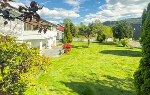 Ein Wohnhaus mit gepflegter Rasenfläche, ein weißes Haus mit rotem Dach und ein großer Baum im Garten.