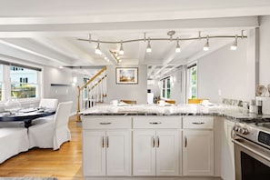 A modern kitchen with white cabinetry, a marble countertop, and a built-in oven.
