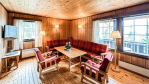 A wooden-paneled room with a sofa, chairs, a table, a TV, and lamps. - Cozy home in Vinstra with sauna (Vinstra)