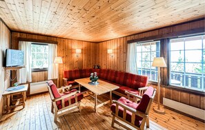 A wooden-paneled room with a sofa, chairs, a table, a TV, and lamps. - Cozy home in Vinstra with sauna (Vinstra)