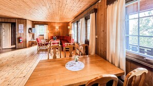 A wooden interior with a dining area, a sofa, and large windows. - Cozy home in Vinstra with sauna (Vinstra)
