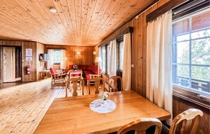 A wooden interior with a dining area, a sofa, and large windows. - Cozy home in Vinstra with sauna (Vinstra)