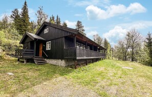 Eine Holzhütte mit Veranda, einer kleinen Treppe und einer Rasenfläche.