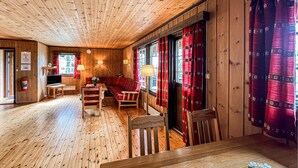 Un intérieur en bois avec un canapé, des fauteuils, un téléviseur et une cheminée.