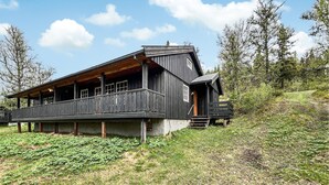 Une cabane en bois dotée d’un balcon, située sur une colline verdoyante.