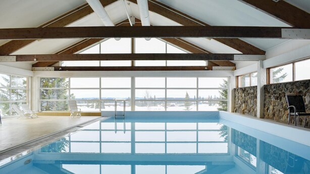 Ein großes Hallenbad mit Blick auf eine verschneite Landschaft durch große Fenster.