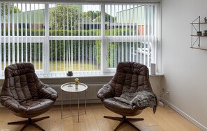 A room with two leather armchairs, a small round table, and a view through large windows with blinds. - 3 bedroom stunning home in Tarm (Tarm)