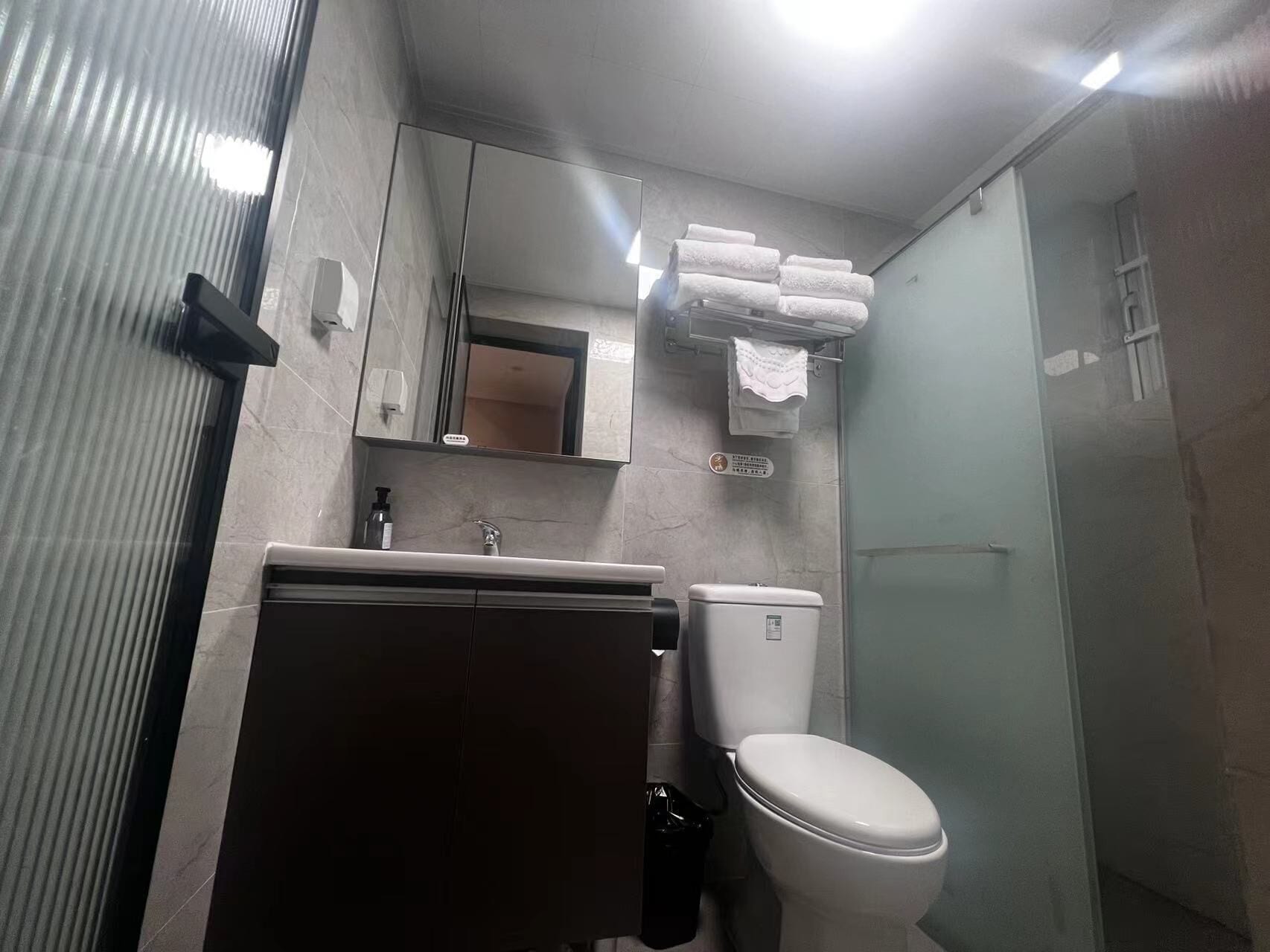 A bathroom with a toilet, sink, mirror, and a towel rack.