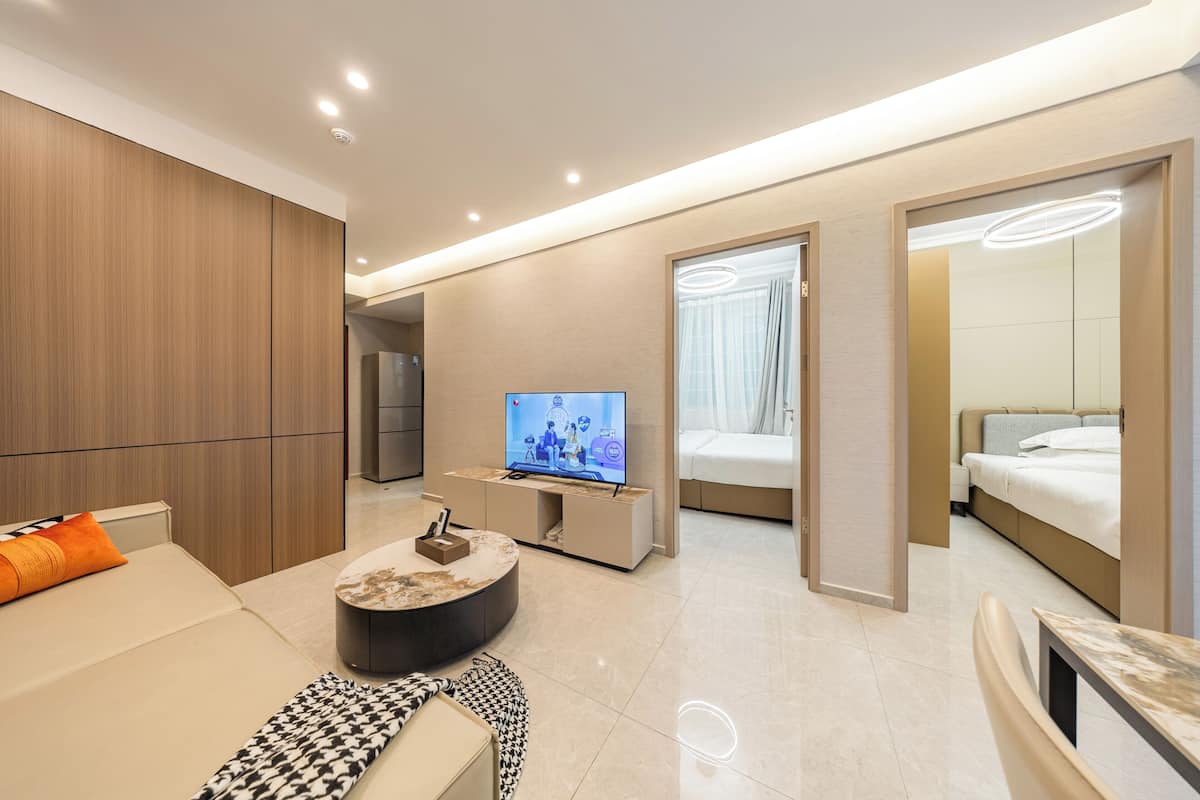 A modern hotel room with a TV, sofa, and a bed.