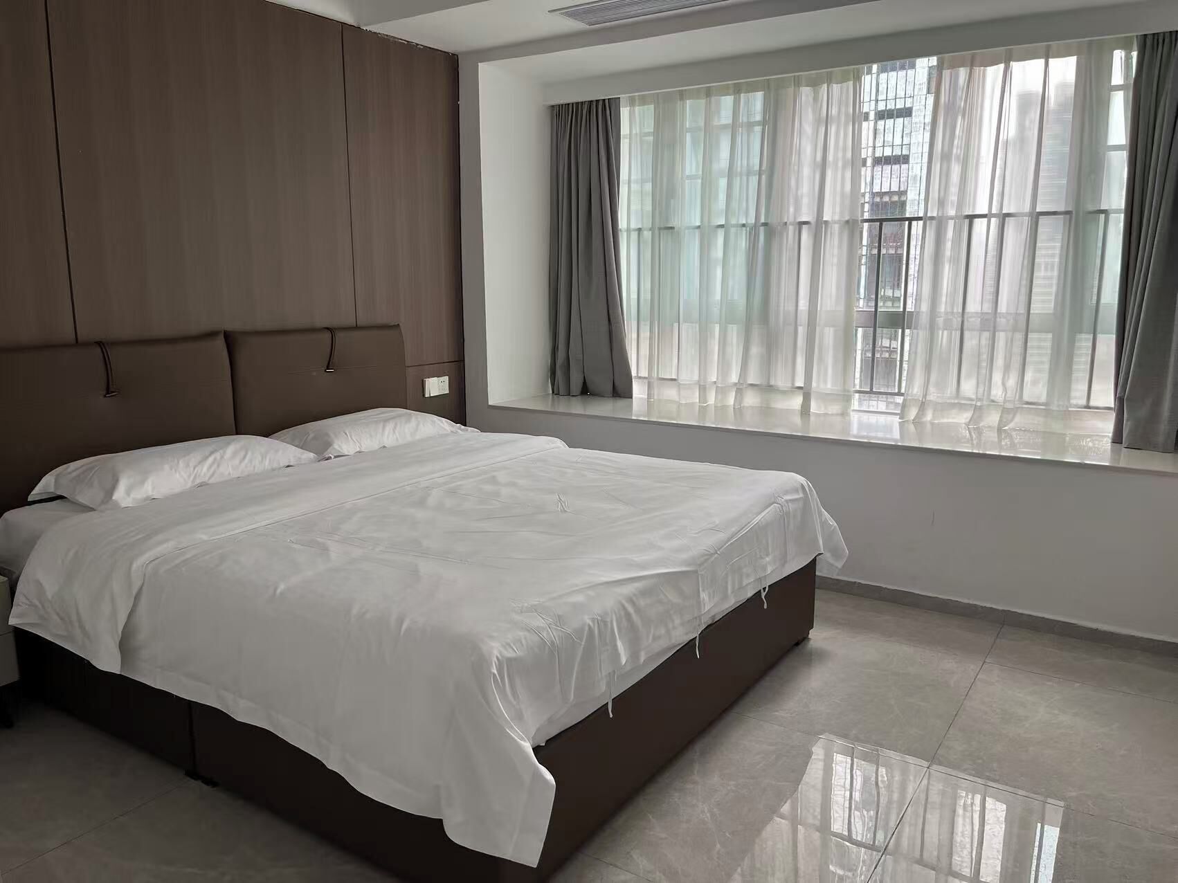 Un dormitorio con una cama grande, un armario y una ventana con cortinas.