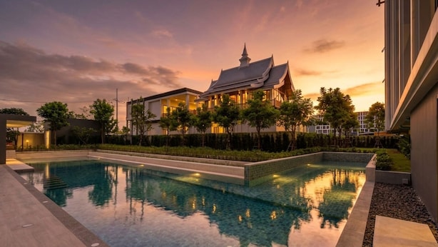 A swimming pool with a traditional house in the background. - New 2 BR Apt Golf View - Ozone 108-156 (Thalang)