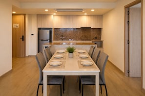 A modern kitchen with a dining table set for six, a built-in oven, and a large window above the sink. - New 2 BR Apt Golf View - Ozone 108-156 (Thalang)
