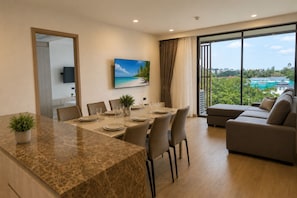 Una sala de estar moderna con comedor, un ventanal con vistas y un televisor de pantalla plana montado en la pared.