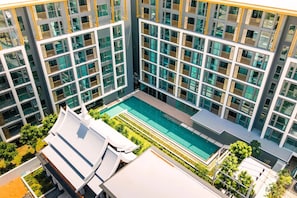 A modern building with a rooftop swimming pool and multiple balconies. - New 2 BR Apt Golf View - Ozone 108-156 (Thalang)
