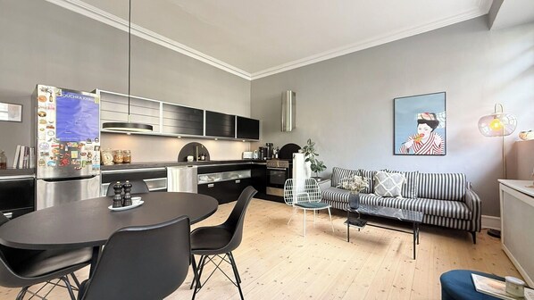 Une cuisine moderne avec un coin repas, un canapé et un tableau au mur.