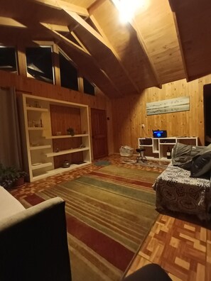 Une piÚce chaleureuse avec un plafond en bois, un canapé, une petite table et une bibliothÚque.